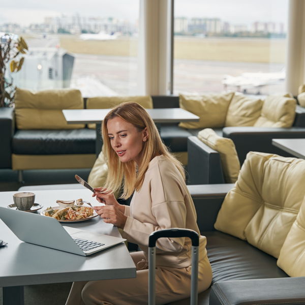 Airport VIP Lounge A young woman with a laptop is sitting in the VIP lounge at Berlin Airport, enjoying her meal.
